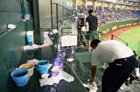 雨漏りで水浸しとなった東京ドームのバックスクリーン横。関係者が拭き取る作業に追われた