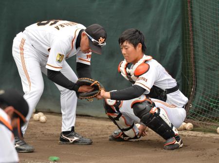 　吉原バッテリーコーチ（左）に捕手の指導を受ける和田
