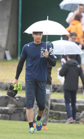 　練習試合中止の決定後、傘を差し球場を移動する日本ハムの大谷