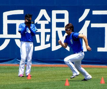 ＤｅＮＡの久保（左）はトレーニングする三嶋を動画で撮影する＝横浜スタジアム