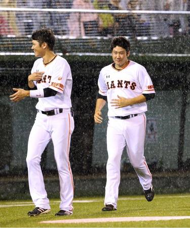　雨で試合が中止となりスタンドのファンにあいさつして引き揚げる菅野と坂本（左）