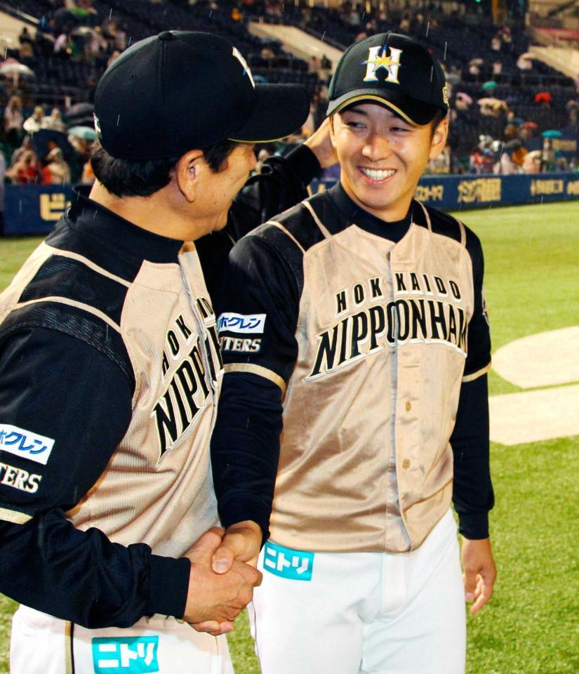 　今季初勝利を挙げ、栗山監督（左）と握手する斎藤佑