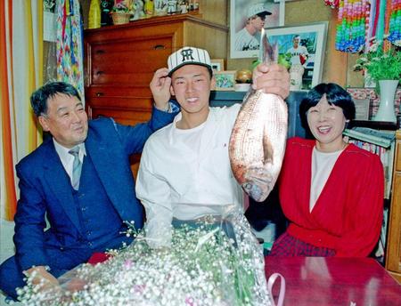 阪神に１位指名され贈られたタイを手にする安達さん（中央）と父・孝四郎さん（左）、母・節子さん（右）＝９２年１１月２１日、神戸市長田区の自宅