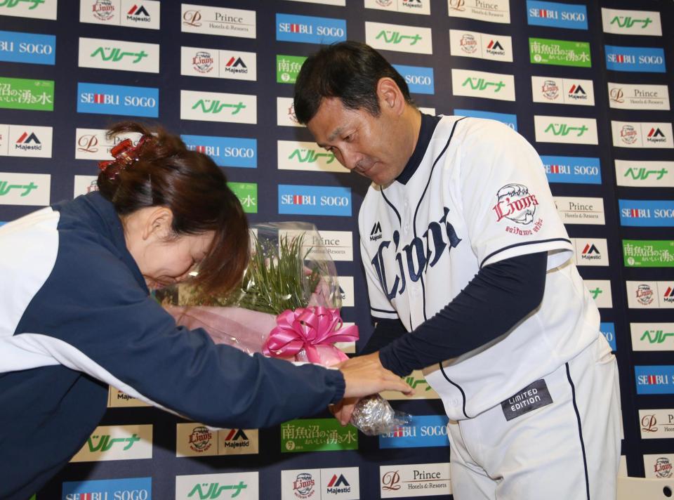 　試合後、退任会見に臨み球団職員から花束を受け取る田辺監督