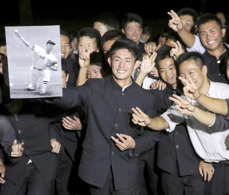 　西武の１位指名を受け、ＯＢの江川卓さんの写真パネルを手に野球部の仲間に囲まれ笑顔を見せる作新学院高校の今井達也