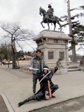 仙台市・青葉山公園の伊達政宗公騎馬像前でポースを取る平沢、右は政宗の重臣として仕えた片倉小十郎重綱に扮した関係者