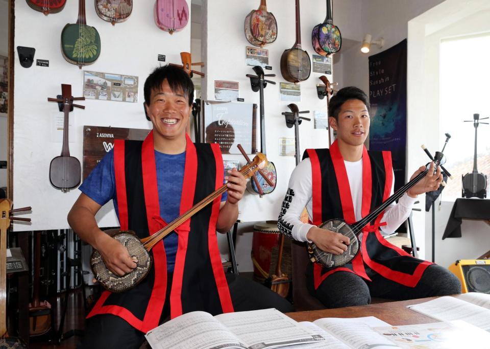 琉球衣装をまとい、三線（さんしん）を弾く柳（左）と京田