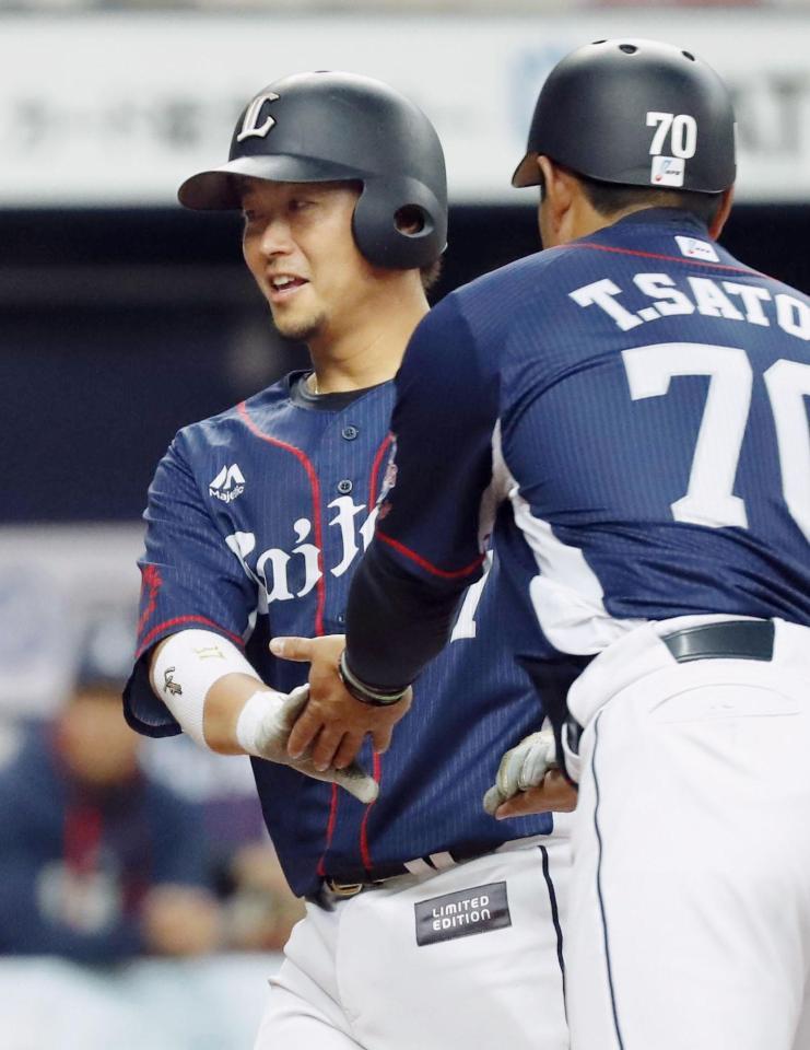 　５回、本塁打を放ち、佐藤コーチ（右）とタッチする西武・岡田