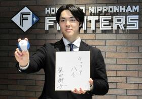 　契約を更改し、来季の目標を記した色紙を手にポーズをとる柴田