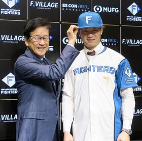 　入団記者会見を終え、撮影に応じる日本ハム・西川。左は栗山ＣＢＯ