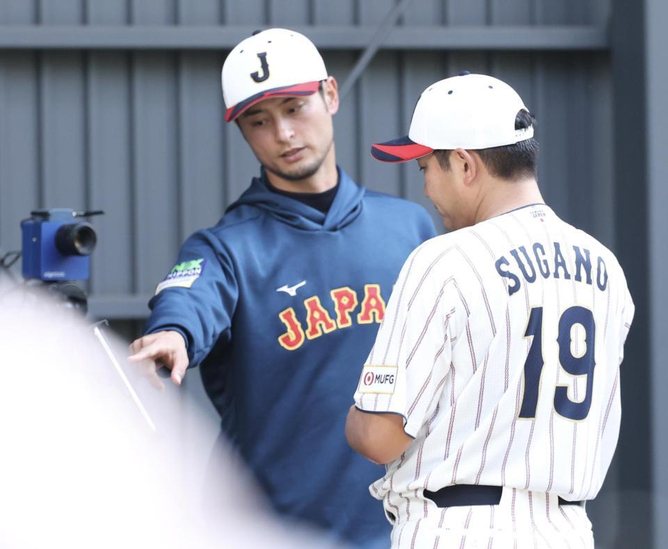 ブルペンでの投球を終え、ダルビッシュ（奥）とデータをチェックする菅野（撮影・伊藤笙子）
