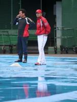 　雨で水浸しとなったグラウンドを見つめる広島・緒方監督（右）