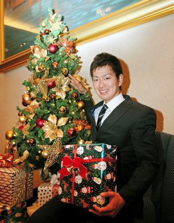 　新入団発表に向け広島入りし、クリスマスツリーを背に笑顔を見せる飯田（撮影・出月俊成）　