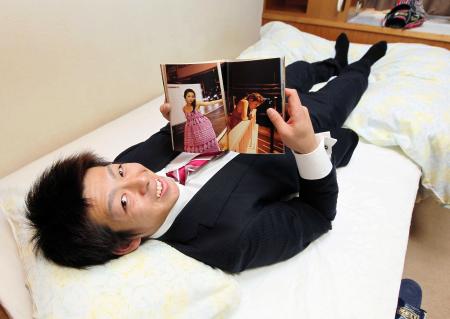 　自室のベッドに寝転び、大島優子の写真集を見る野間（撮影・出月俊成）