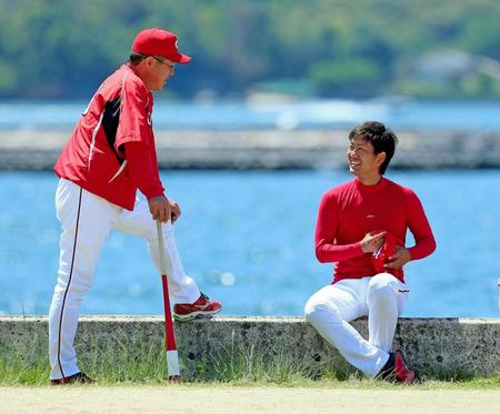　海沿いに腰掛けて佐々岡コーチ（左）と談笑する飯田