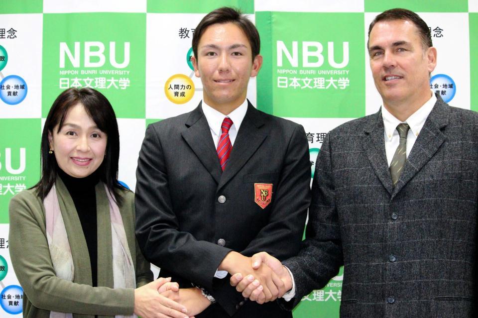 仮契約を終え、母・陽子さん（左）、父・ブルースさん（右）と握手するケムナ
