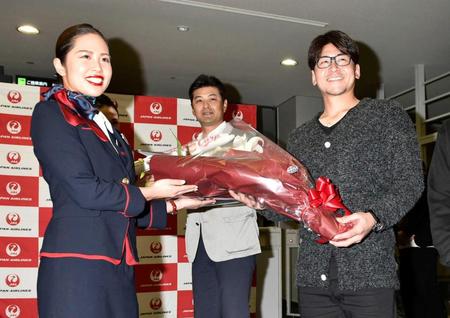 　優勝旅行の出発セレモニーで花束を受け取る会沢（右）。中央は緒方監督