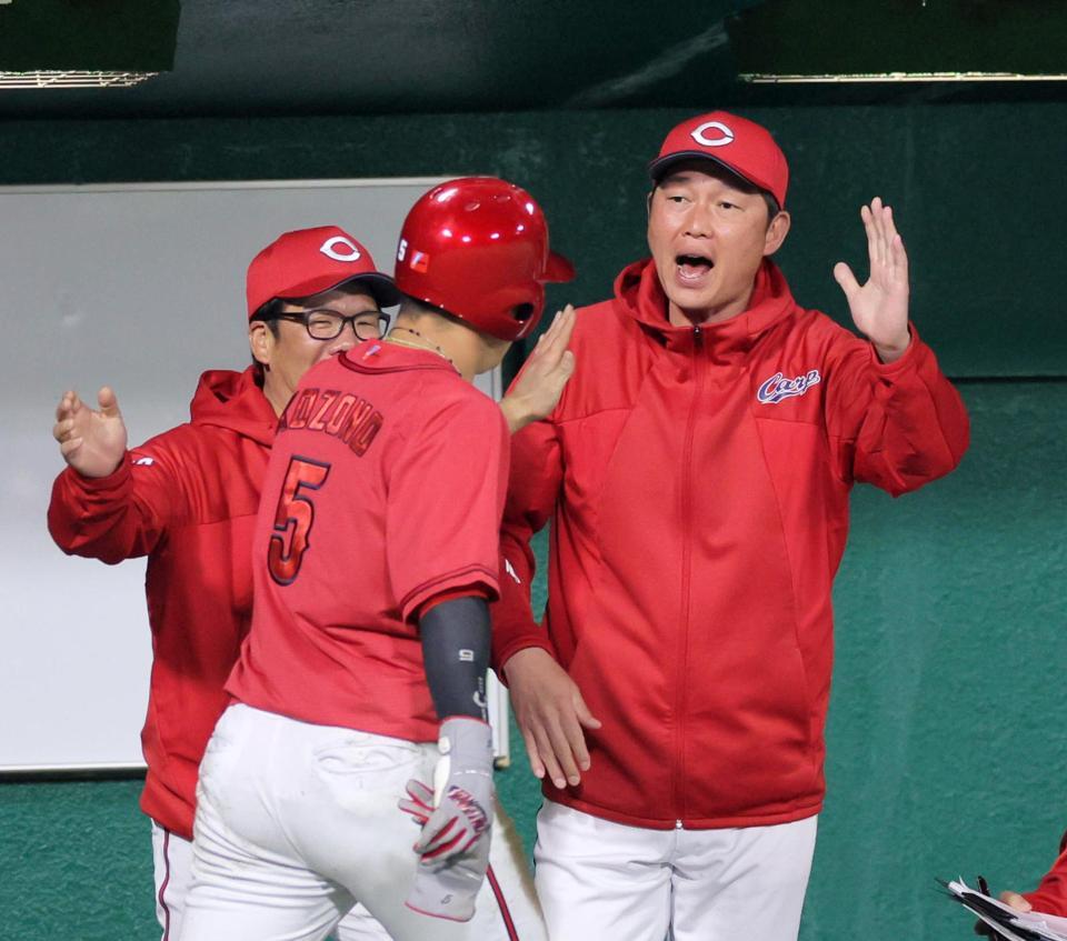 　７回表、同点の生還をした小園を迎える新井監督（右）