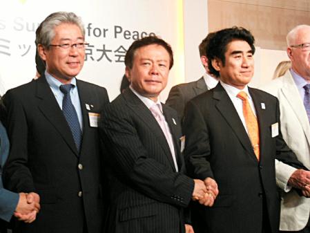 　壇上で握手を交わす（左から）竹田ＪＯＣ会長、猪瀬都知事、半田スポーツ平和サミット実行委員長