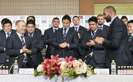 　記者会見を終え、リーチ・マイケル主将（前列右）の合図で手をたたくラグビー日本代表。前列左はエディー・ジョーンズ・ヘッドコーチ、中央は五郎丸歩選手＝13日午後、東京都内のホテル