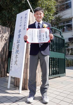 東京・稲付中の正門前で、卒業証書を手にする卓球男子の張本智和選手=20日午後、東京都北区