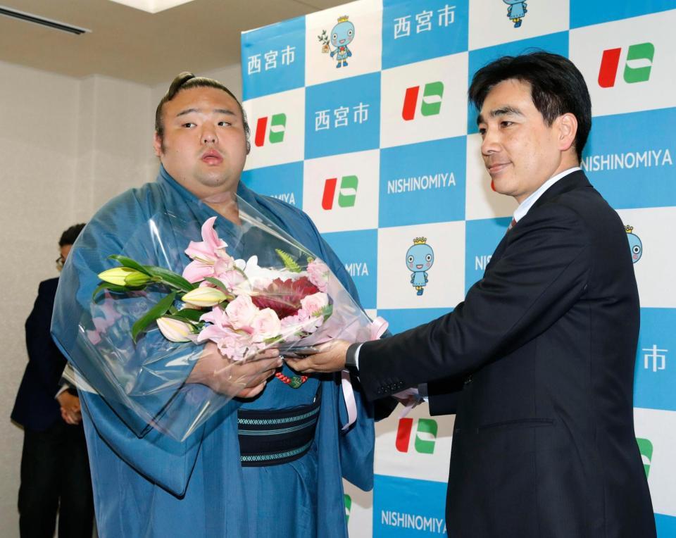 　兵庫県西宮市役所を表敬訪問し、石井登志郎市長（右）から花束を受け取る貴景勝