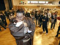 　避難所で暮らす被災者の赤ちゃんを抱き上げ、キスをする白鵬＝２０１１年４月９日、福島県・石川町の総合体育館
