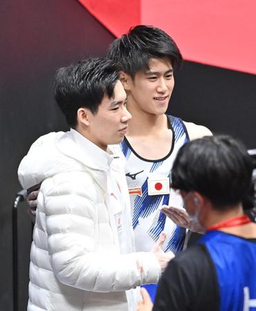 男子個人総合で優勝した中国の張博恒（左）と写真に納まる２位の橋本大輝