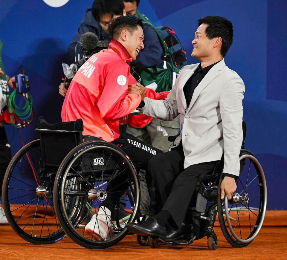 　車いすテニス男子シングルスで優勝した小田凱人（左）と握手する国枝慎吾さん