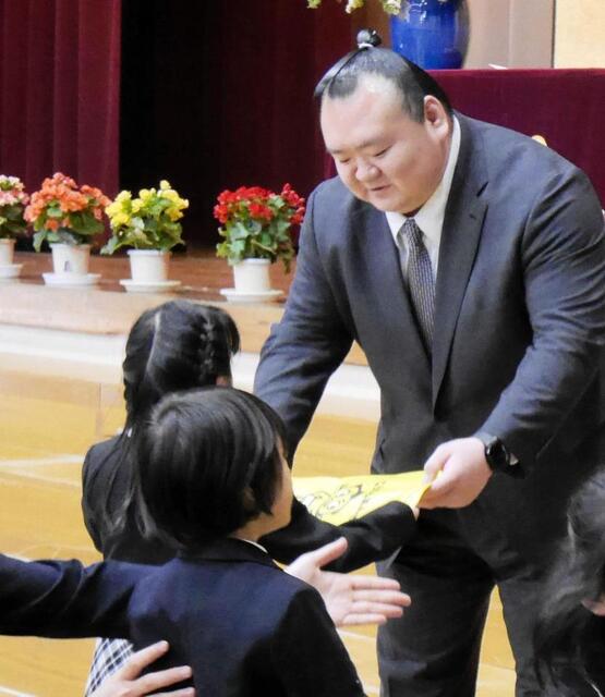 新入生にランドセルカバーを手渡す桐山親方＝都内