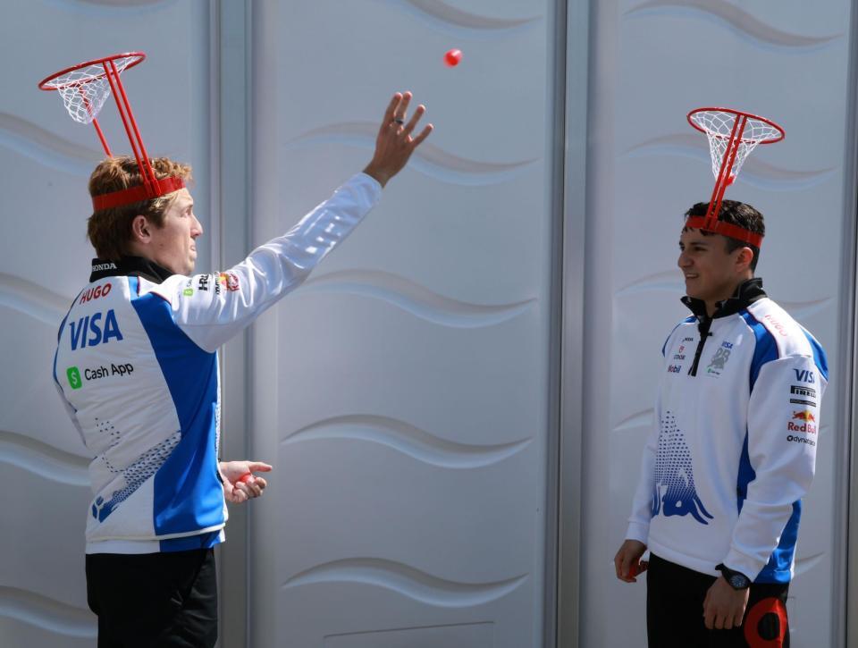 　頭に乗せたカゴにボールを投げ入れるレーシングブルズ・ホンダのアイザック・ハジャー（右）とリアム・ローソン（撮影・神子素慎一）