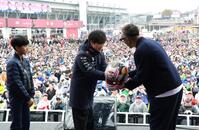 　ヘルメットにサインし市川團十郎に手渡すレッドブル・ホンダの角田裕毅。左は市川新之助（撮影・神子素慎一）