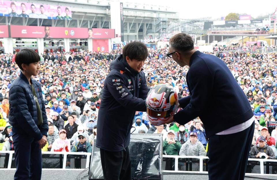 　ヘルメットにサインし市川團十郎に手渡すレッドブル・ホンダの角田裕毅。左は市川新之助（撮影・神子素慎一）