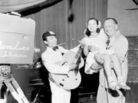 米ロサンゼルスでテレビに出演、司会のアンクル・グラニーさんに抱き上げられ歌う美空ひばりさんと伴奏の川田晴久さん=1950年7月(共同)