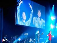 VTRに映し出された故青山孝史さんと故北公次さんをバックに熱唱する江木俊夫(左)とおりも政夫=東京・目黒雅叙園