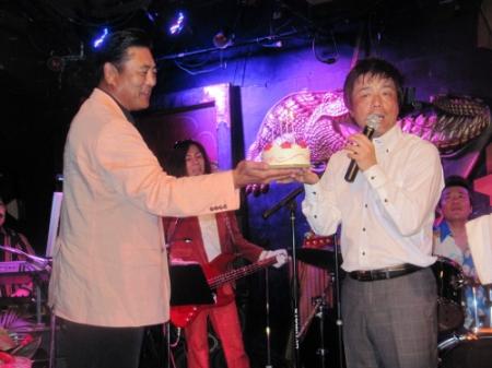 サプライズ登場した陸奥親方（左）からバースデーケーキを贈られる長江健次＝東京・原宿のクロコダイル