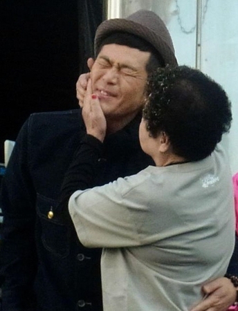 おばちゃん１号にキスされるココリコの遠藤章造（左）と、爆笑する「よしもとクリエイティブ・エージェンシー」の藤原寛常務取締役（右）＝東京・新宿