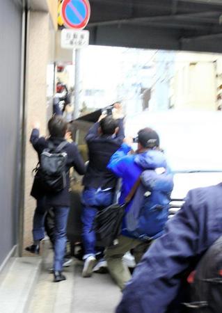 車が横付けされ、黒いシートが張られた通用口に集まる報道陣＝高松市内