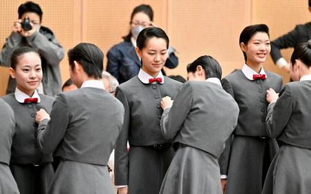 　宝塚音楽学校の入学式で、在校生（手前側）から校章バッジをつけてもらう新入生