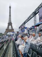 　雨の中、開会式が行われるトロカデロ庭園で開幕を待つ観客。奥はエッフェル塔（共同）