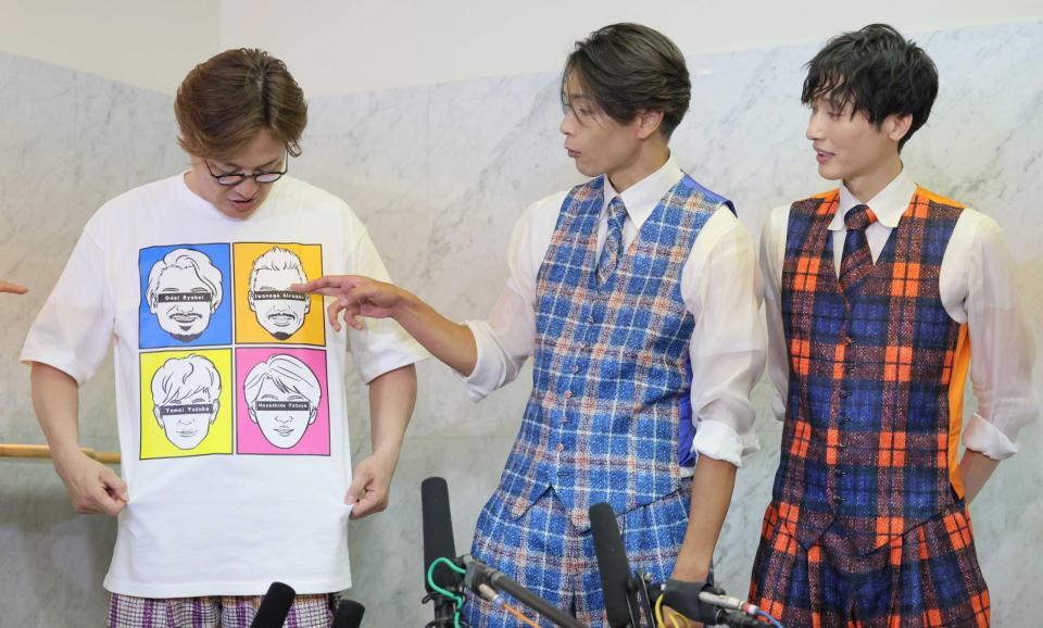　脱退したメンバーの顔が描かれたＴシャツを着て会見する酒井一圭（左）