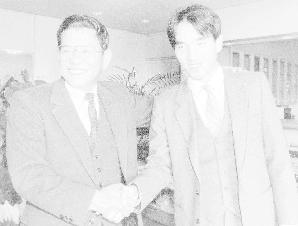 　指名あいさつで栗田（右）と握手をかわし笑顔の備前喜夫スカウト＝１９８６年１１月２８日