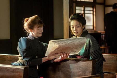 宣教師・メアリー（アニャ・フロリス）と、英字新聞で捨松の結婚披露の記事を読む直美（上坂樹里）