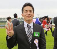 　三本指を立てて笑顔のノーザンファームしがらき・鈴木厩舎長
