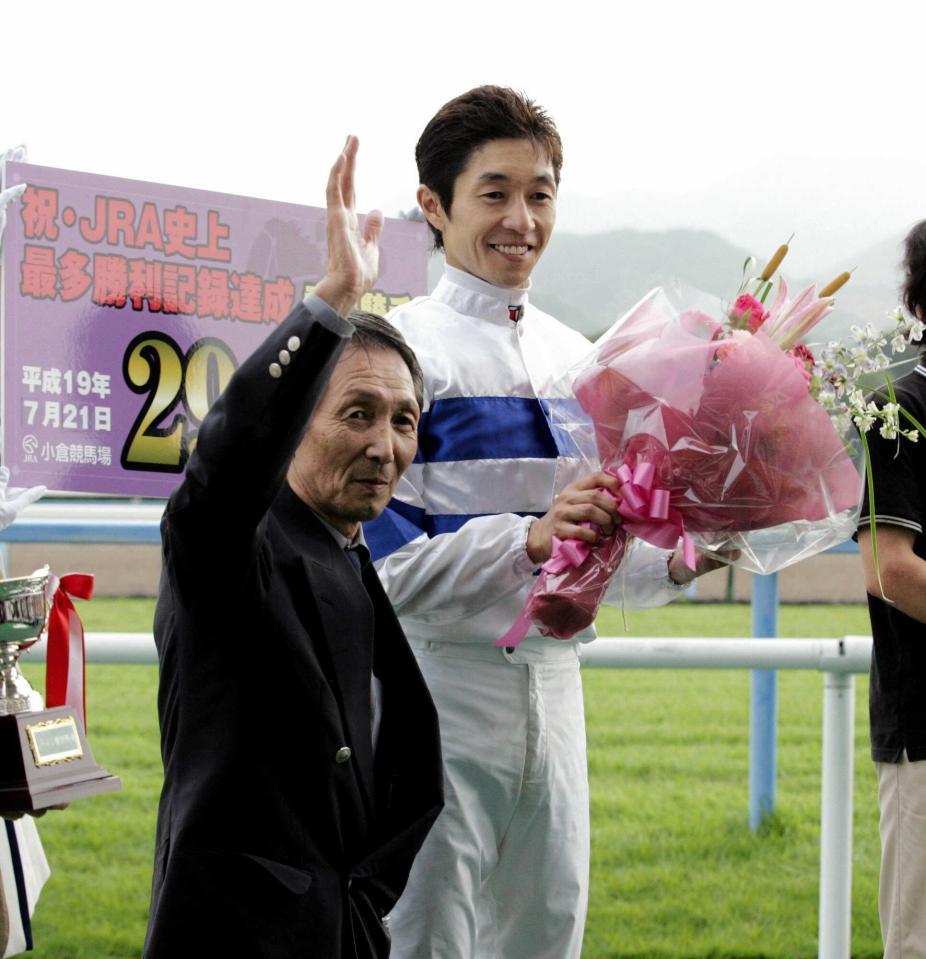 　ＪＲＡ最多勝利記録を更新した武豊は、父・武邦彦調教師（左）から花束を受け取り笑顔を見せる＝０７年７月２１日、小倉競馬場