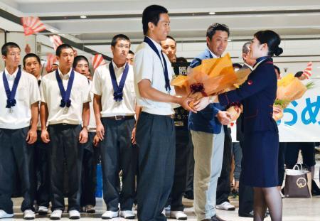 　新千歳空港に到着し、花束を受け取る北海高校の大西健斗主将（手前左）＝２２日午後