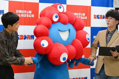　『たくろう万博』の会見で、ミャクミャクと手を繋ぐ（左から）赤木、きむらバンド（７月３日・大阪市内）