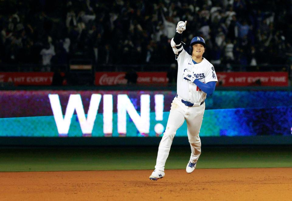 　外野フェンスに浮かぶ「ＷＩＮ！」の文字を背に塁を回る大谷（共同）