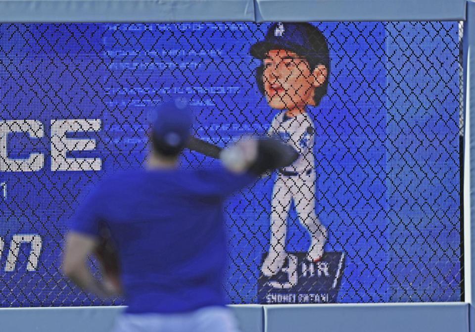 キャッチボールする大谷（手前）と、自身の首振り人形のモニター（共同）