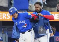 　ガーディアンズ戦の４回、５号ソロを放ち、ゲレロ（右）に祝福のジャケットを着せてもらう岡本（共同）